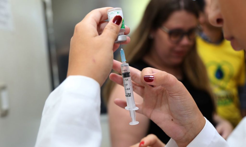 Profissional de saúde preparando a vacina da gripe para aplicação em paciente