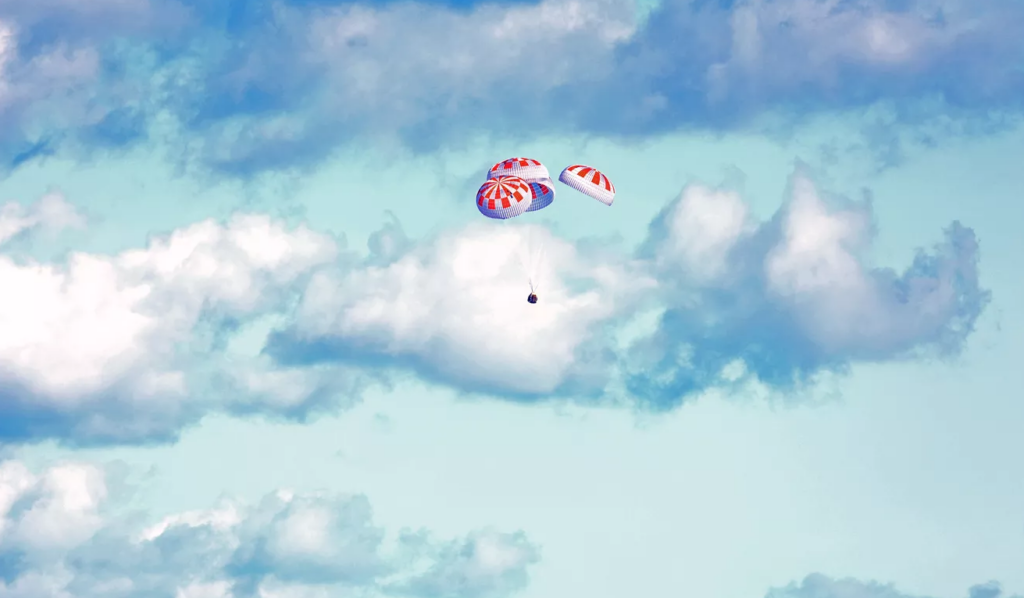 Cápsula crew dragon com paraquedas ativados retornando à terra