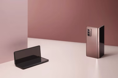Galaxy z fold 2, o último dos smartphones dobráveis da samsung, nas cores bronze e preto, dobrados em cima de uma mesa rosa clara