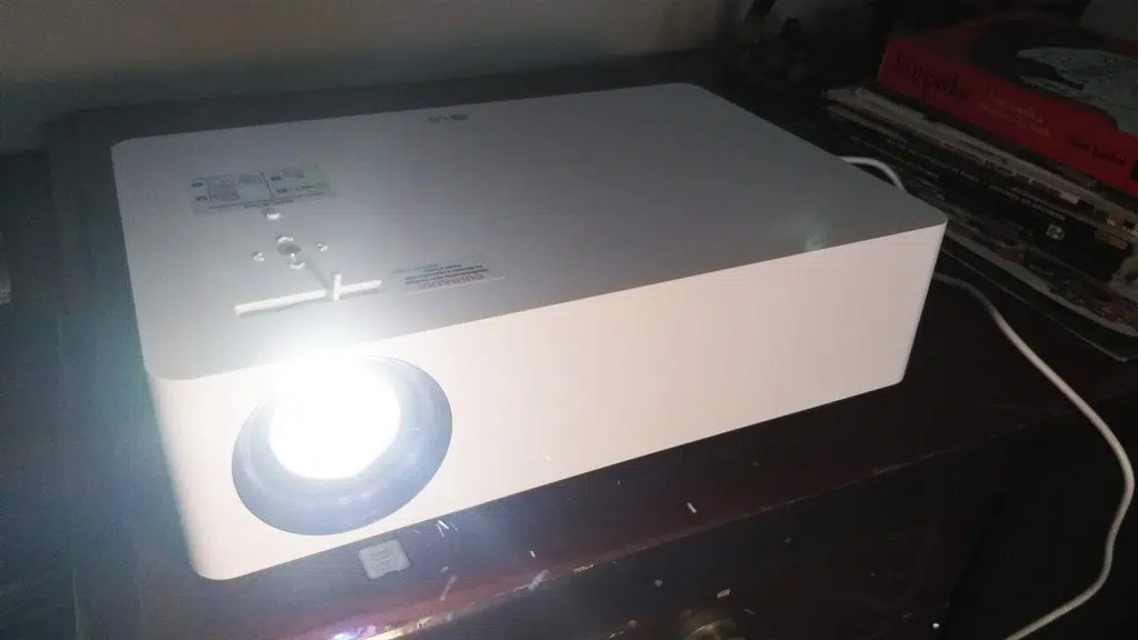 Review: projetor 4k lg cinebeam tv, o excelente substituto para a tela de cinema Lg cinebeam no escuro sobre mesa de madeira