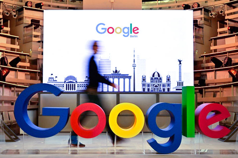 Em imagem, homem caminha frente a um logo do google
