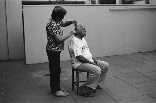 Cena do cotidiano de um casal, maria e josé, com ela cortando os cabelos dele - acervo museu da imagem e do som