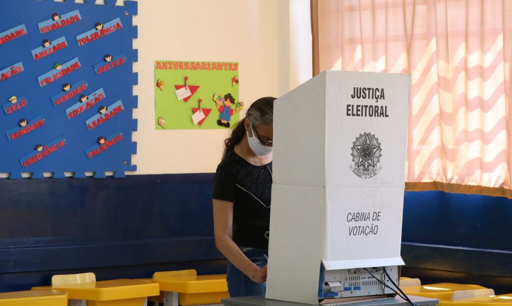 Mulher realizando votação em urna eletrônica