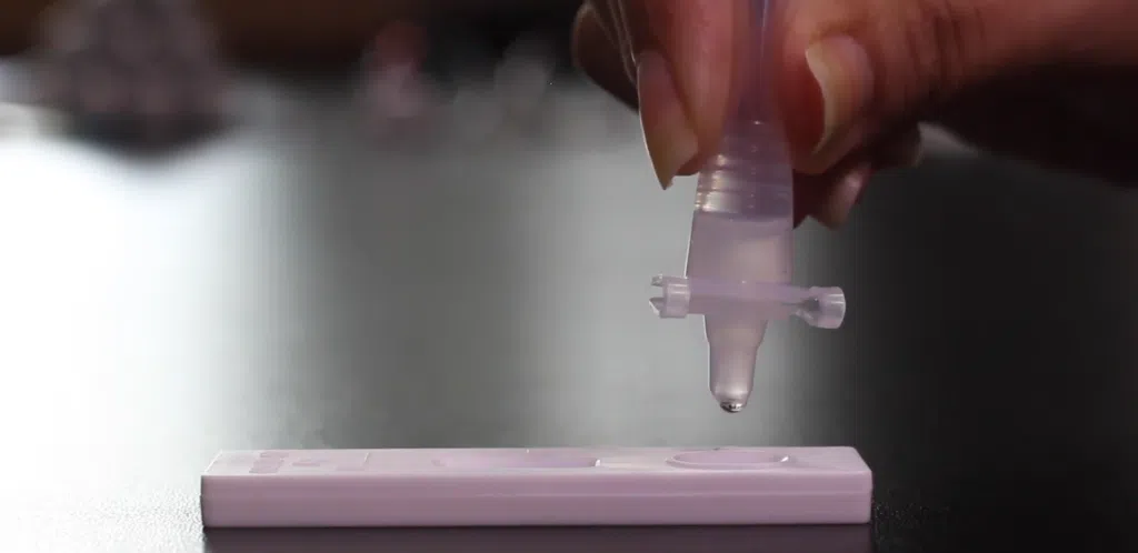 Como funciona e onde comprar autoteste de covid-19 Mulher segurando tubo com reagente do autoteste de covid-19