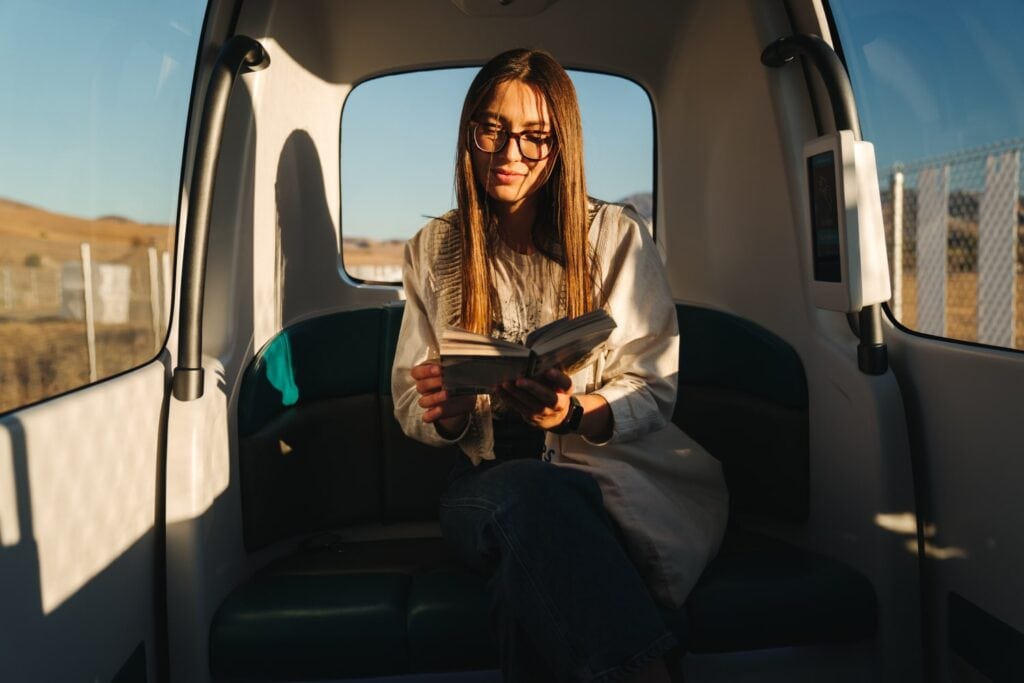 Mulher lendo livro dentro de um carro autônomo da glydways