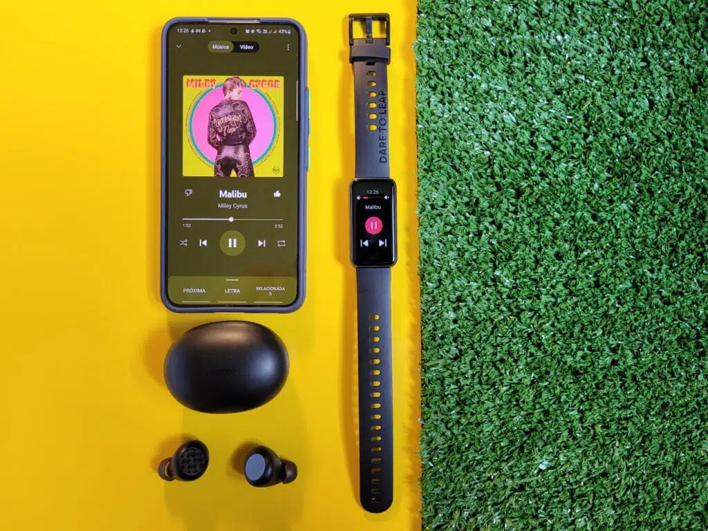 Review: smartband realme band 2 Realme band 2 em cima de fundo amarelo ao lado de grama com galaxy s22 e realme buds q2