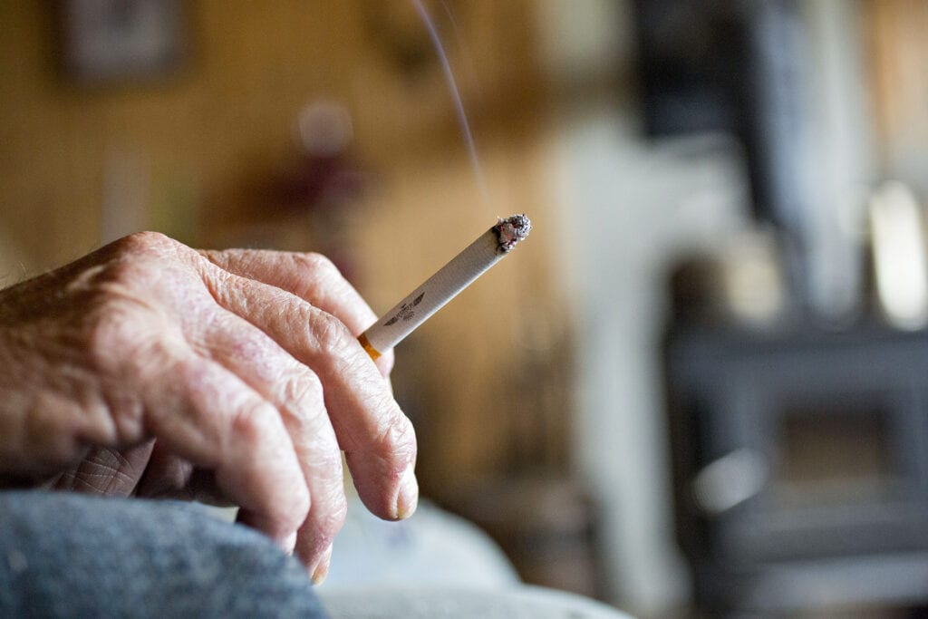 Homem idoso segurando cigarro tradicional