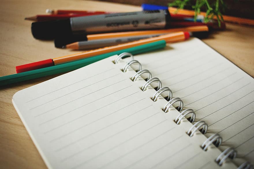 Caderno e canetas sobre uma mesa de escritório