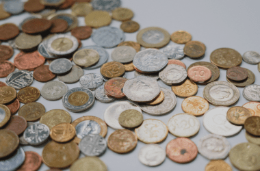 A foto mostra diversas moedas de centavos de diferentes moedas, como real, dólar, euro, entre outras