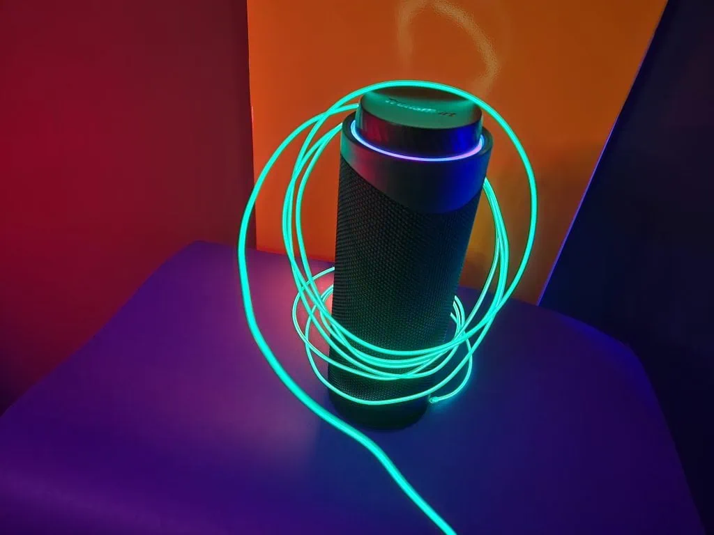 Gjennomgå tronsmart t7: liten og veldig kraftig Tronsmart t7 bærbar høyttaler på gul bakgrunn, med grønn led ledning