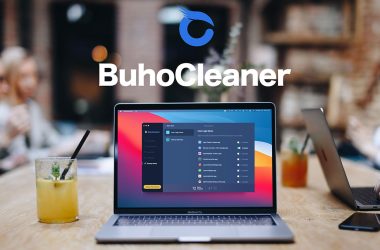 Macbook com buhocleaner aberto, em cima de uma mesa ao lado de outros laptops e um copo de suco