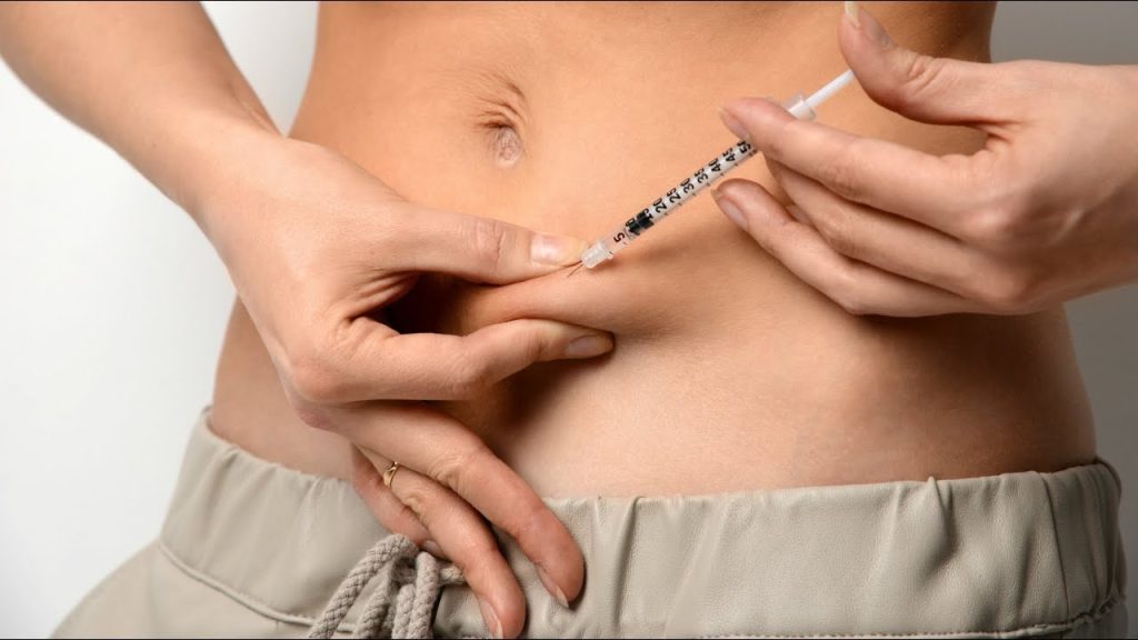 Mulher aplicando uma injeção de insulina na barriga