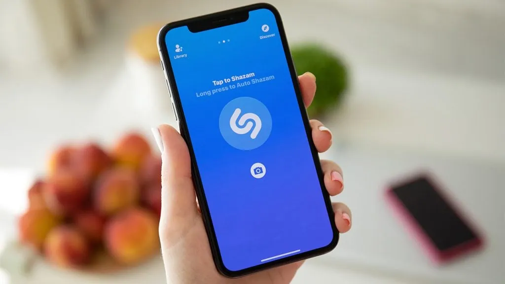 Os melhores apps para iphone (ios) em 2023 Pessoa segurando iphone com o aplicativo do shazam aberto
