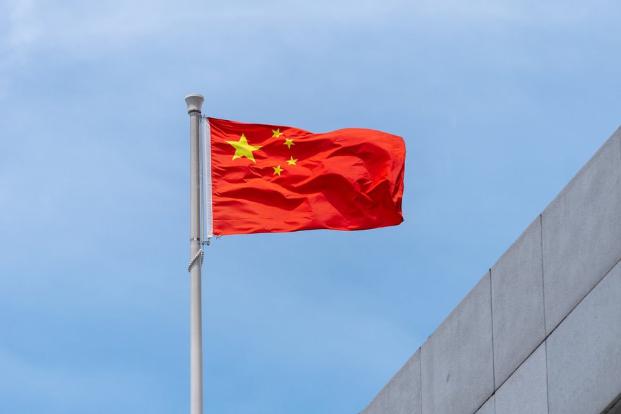 Bandeira chinesa ao vento contra céu azul claro.