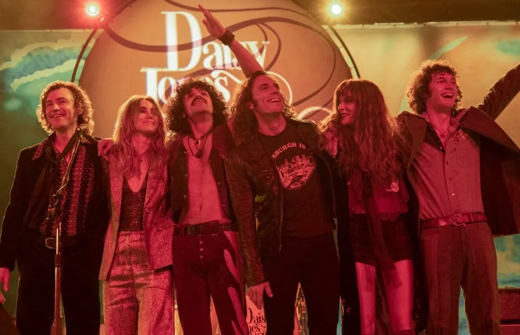 Tudo sobre a série "daisy jones and the six" do prime video Daisy jones and the six juntos após o final de um show, em cena da série do amazon prime video.