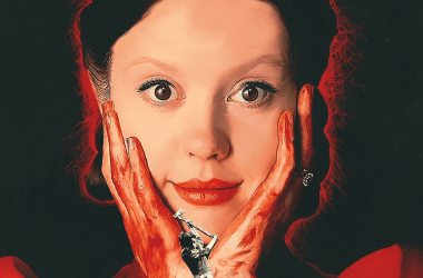Semana do cinema 2023 terá o filme "pearl" em exibição. Pôster mostra a atriz mia goth olhando para frente com um leve sorriso, e suas mãos estão com sangue, apoiadas nas bochechas.