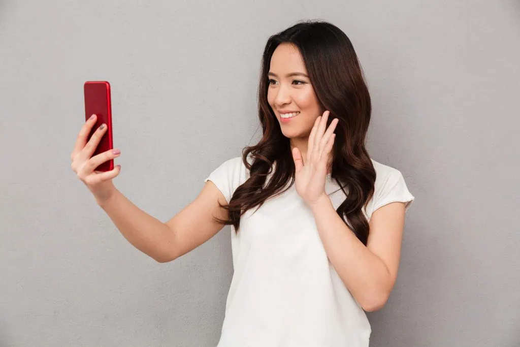 Como tirar a selfie perfeita (guia de fotografia) Mulher tirando selfie perfeita com apoio de iphone