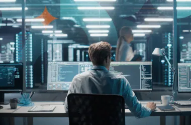 1. Homem programando em ambiente de data center com múltiplas telas de código.