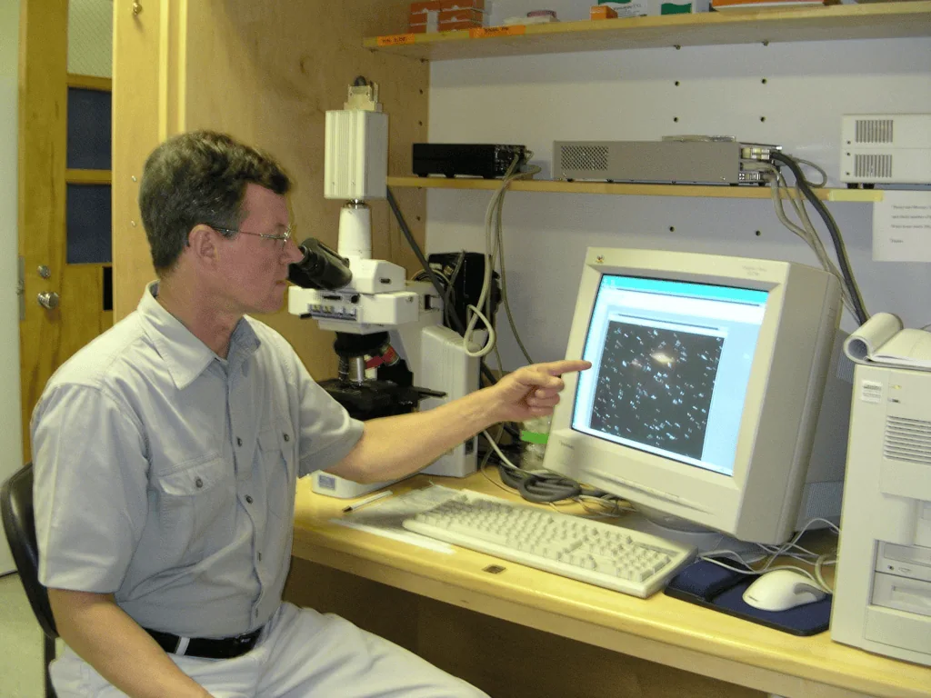 Nova tecnologia transforma ar em eletricidade Geração de energia t alt | lovley aponta para tela de computador com uma bactéria em uma imagem