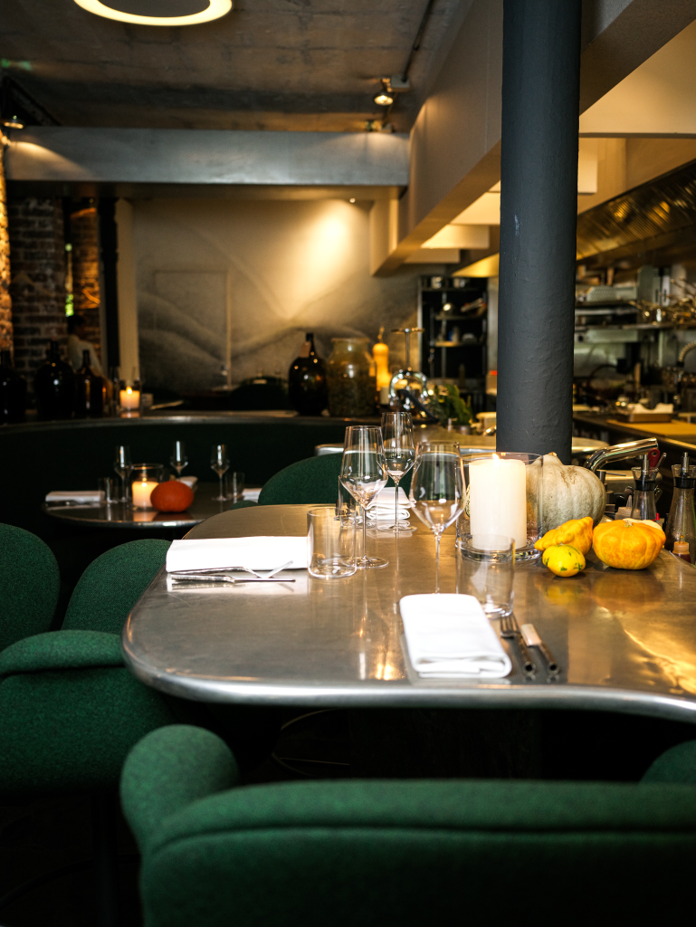 Menu do restaurante t alt table interior mostrando mesa iluminada com luz amerla e ambiente com detalhes em cores escuras