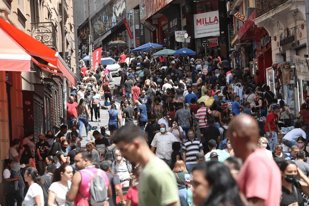 Saiba o que o censo 2022 revela sobre a população do brasil Série histórica do ibge t alt pessoas vestidas com roupas longas de diferentes cores numa rua, com grande número de indivíduos na parte superior, dando uma impressão de eleveção do local