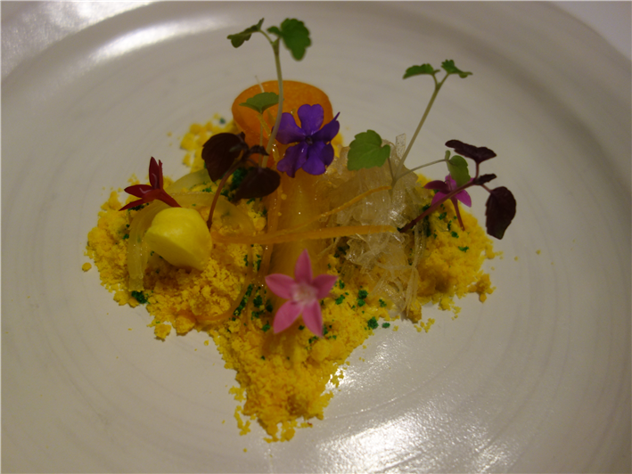 Menu do restaurante t alt 20 prato florido, com cor predominante amarela, e algumas pétalas de flores e folhas em cor verde; o prato é de cor branca