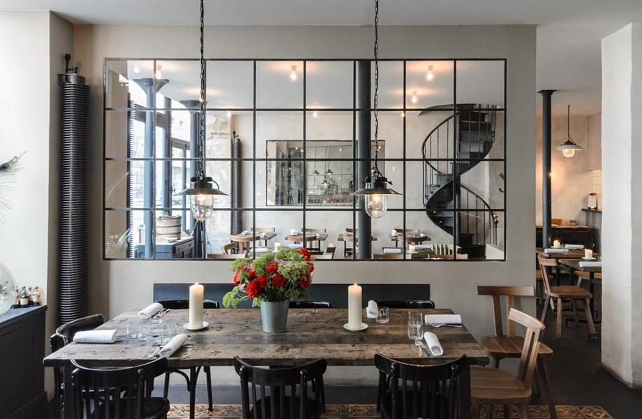 Menu do restaurante t alt 24 ambiente claro com mesa ao centro; acima, janela de vidro, com vista para uma escada à dir.