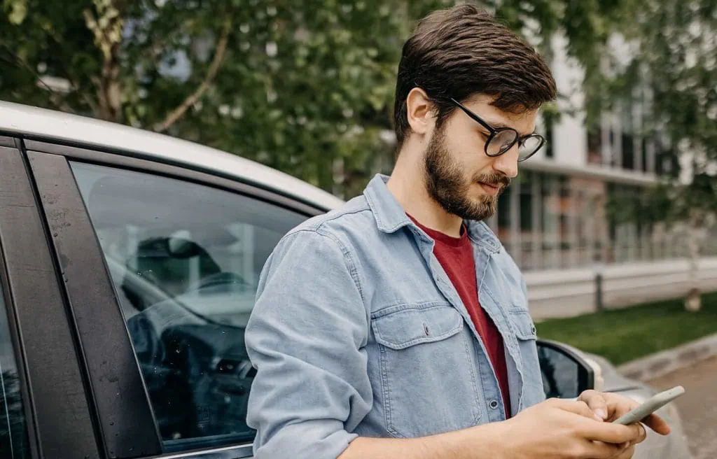 Cómo presentar una queja con Uber o denunciar a un conductor Hombre con la intención de presentar una queja en uber con un teléfono inteligente Android al aire libre