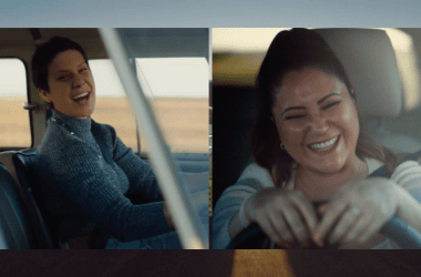 Mulher feliz dirigindo na estrada com câmera na mão, sorriso e diversão ao viajar de carro.