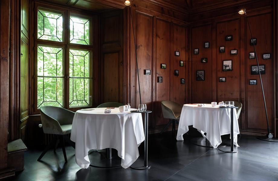 Menu do restaurante t alt 26 local com cores de madeira e mesas dispostas próximas a uma janela, que está na parte esq da imagem