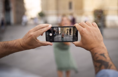 1. Pessoa tirando selfie com smartphone em local urbano movimentado.