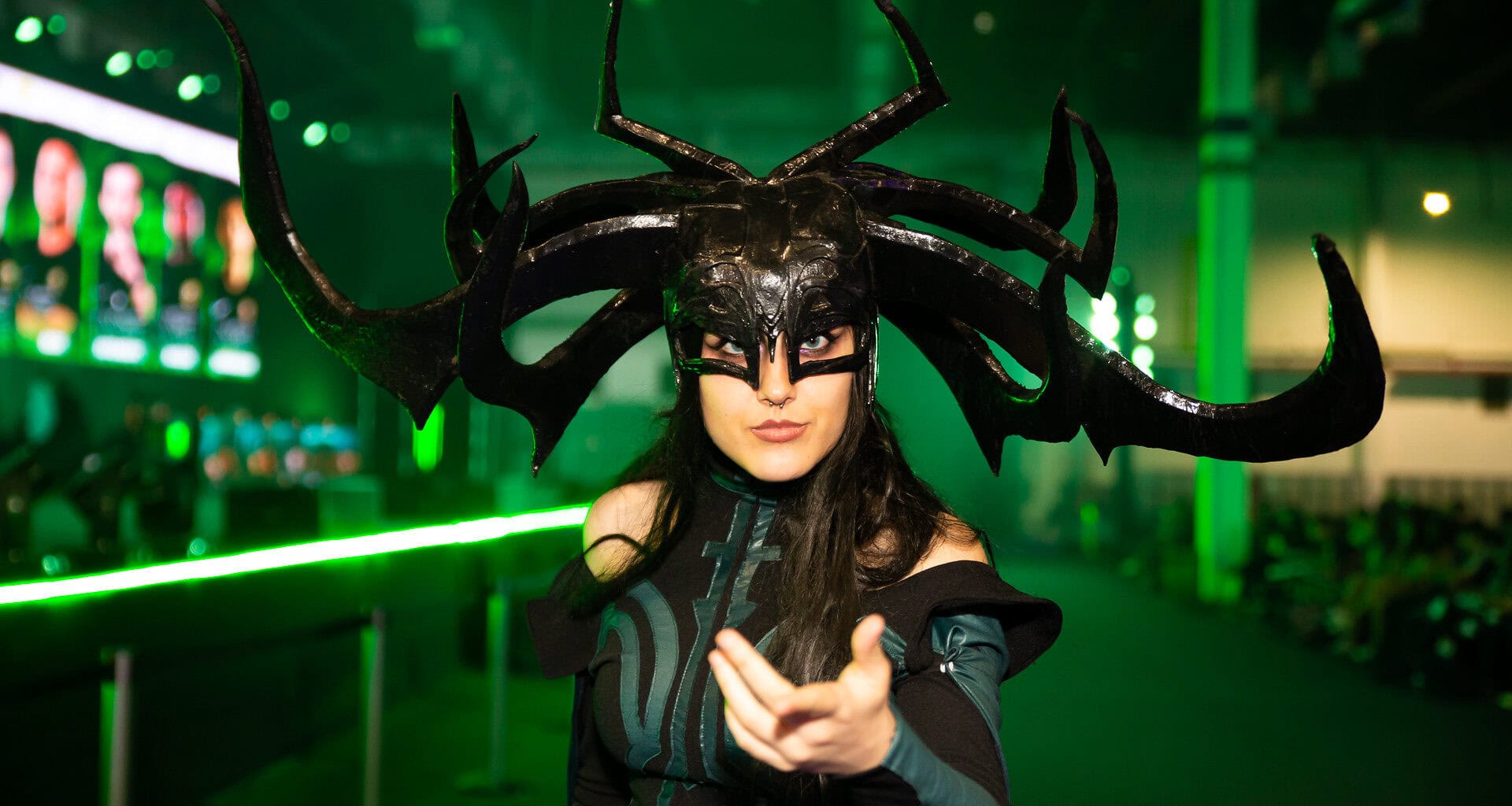 Arte cosplay de personagem com fantasia sombria e headpiece impressionante, cenário de evento de cultura pop.