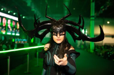 Arte cosplay de personagem com fantasia sombria e headpiece impressionante, cenário de evento de cultura pop.