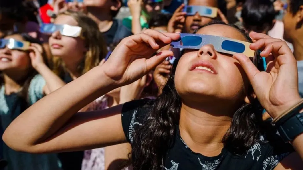 Menina observando eclipse solar anular 