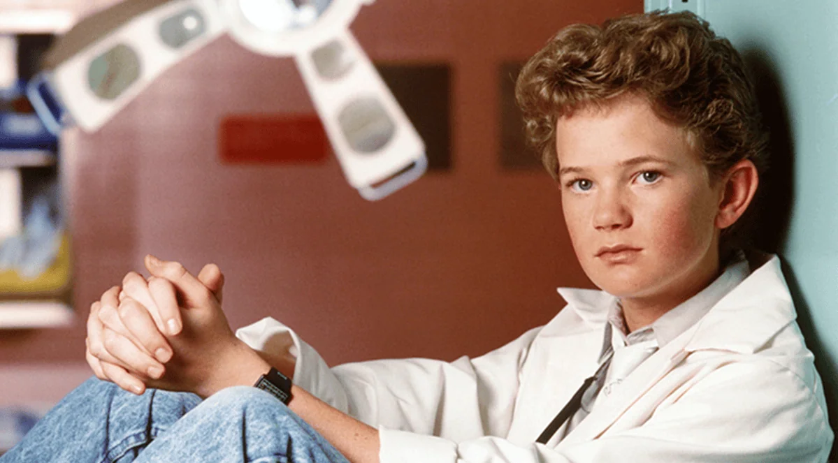 Antes x depois: veja como estão atores mirins hoje! Menino sério com relógio, sentado no chão, clima introspectivo, foto de filme clássico, showmetech.