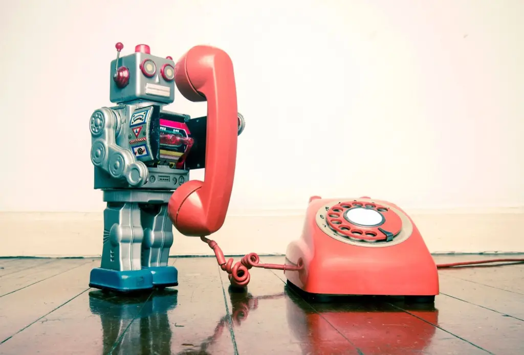 Imagem de um robô usando um telefone antigo - as robocalls fazem parte do cotidiano brasileiro hoje também, adicionando mais irritações à nossa rotina (imagem: digital information world)