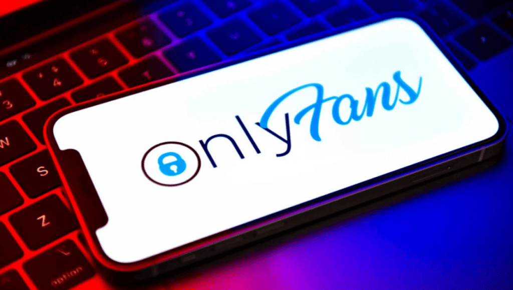 Onyfans, plataforma de conteúdo exclusivo, acessada por smartphone com teclado iluminado ao fundo.