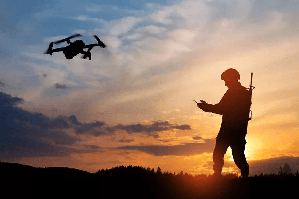 Drone militar com operador controlando à noite durante pôr do sol.