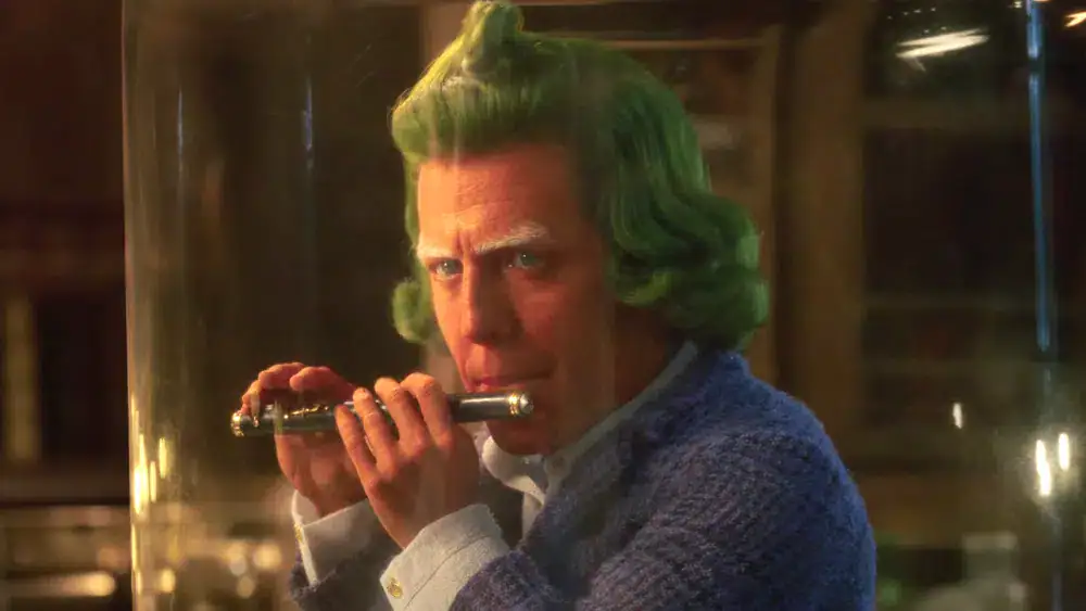 Homem com cabelo verde segurando uma arma em cena de filme de suspense.