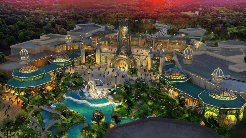 Parque de diversões iluminado à noite, com atrações, jardins e fonte de água exuberantes.