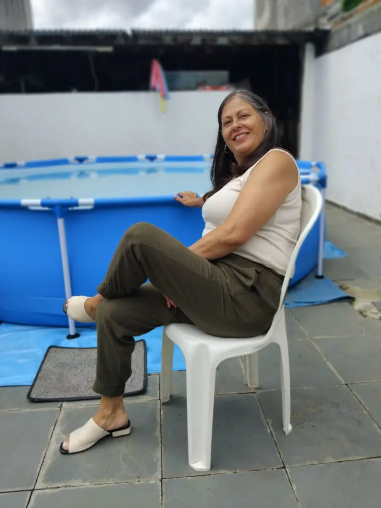 Mulher sentada em banco com piscina ao fundo