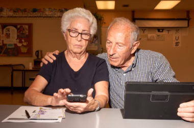 Avó e avô usando smartphone e tablet em ambiente escolar, tecnologia e idosos.