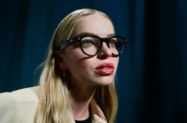 Óculos de armação preta da ray-ban com lentes transparentes, mulher com cabelos loiros e fundo escuro.