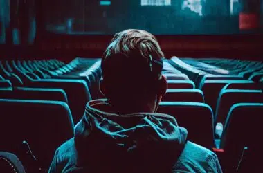 1. Jovem assistindo filme com fones de ouvido em cinema escuro, tecnologia de entretenimento.