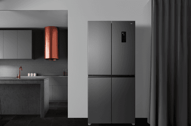 Refrigerador de aço escuro em cozinha moderna com detalhes em cobre e detalhes minimalistas.