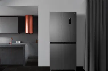 Refrigerador de aço escuro em cozinha moderna com detalhes em cobre e detalhes minimalistas.