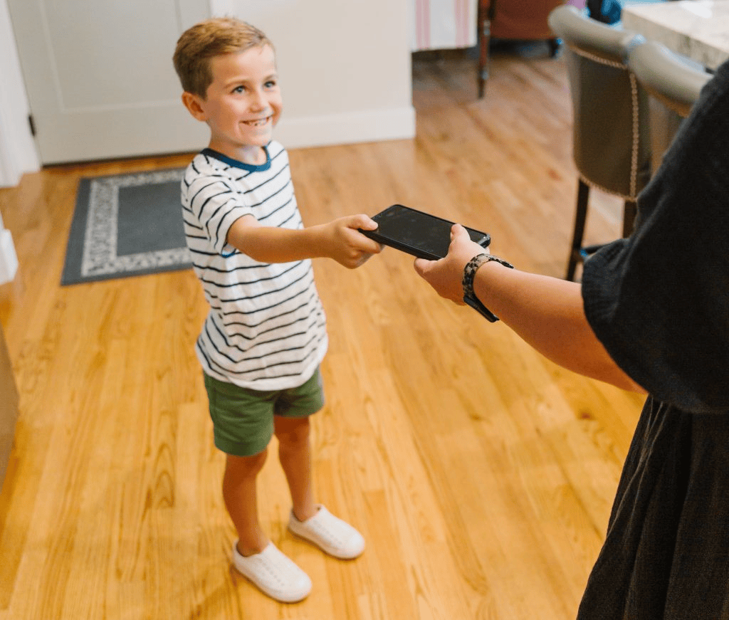 Amigo entregando celular para criança em casa, tecnologia, diversão, conexão, infância, dispositivos eletrônicos.