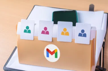 Ícones de contatos e smartphone em pasta com logo do gmail e gmail aberto em fundo de escritório.