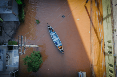 Bacia de alagamento com barco navegando, força da chuva causa enchente urbanas, situação de emergência.