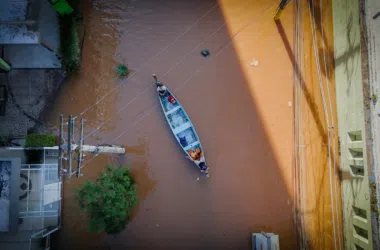 Bacia de alagamento com barco navegando, força da chuva causa enchente urbanas, situação de emergência.